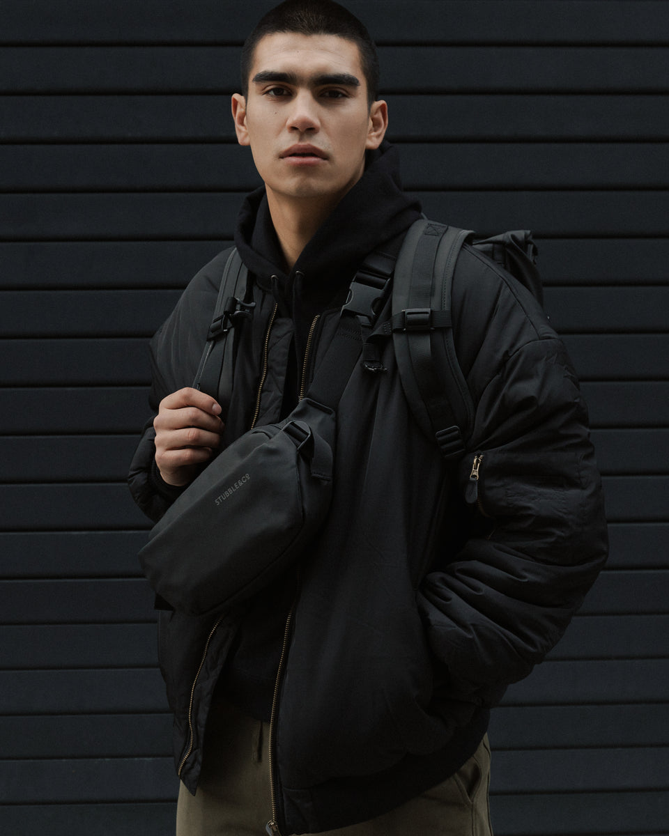 Man wearing a black crossbody bag and backpack