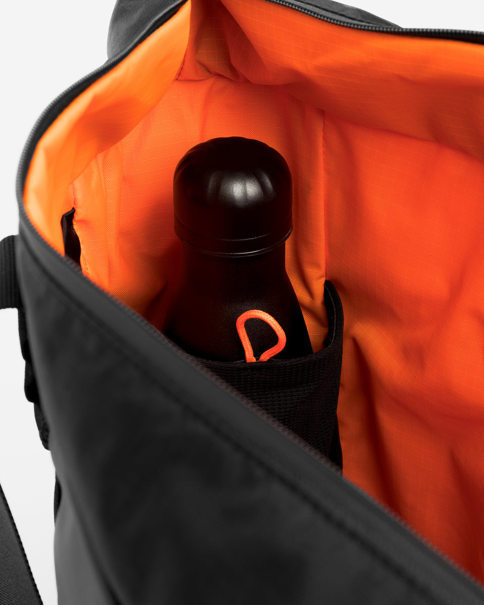 Close up of the inside of a black tote bag with an internal water bottle pocket