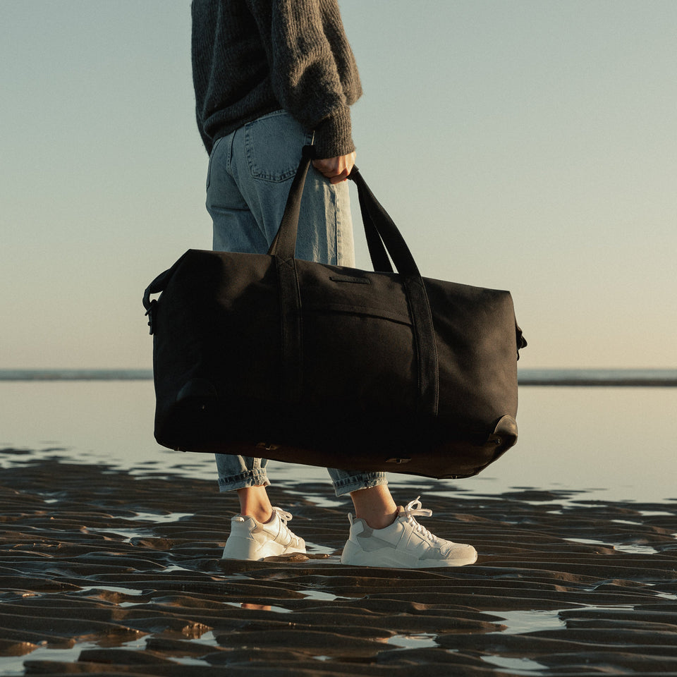 Weekender XL Duffle Bag being held on a beach