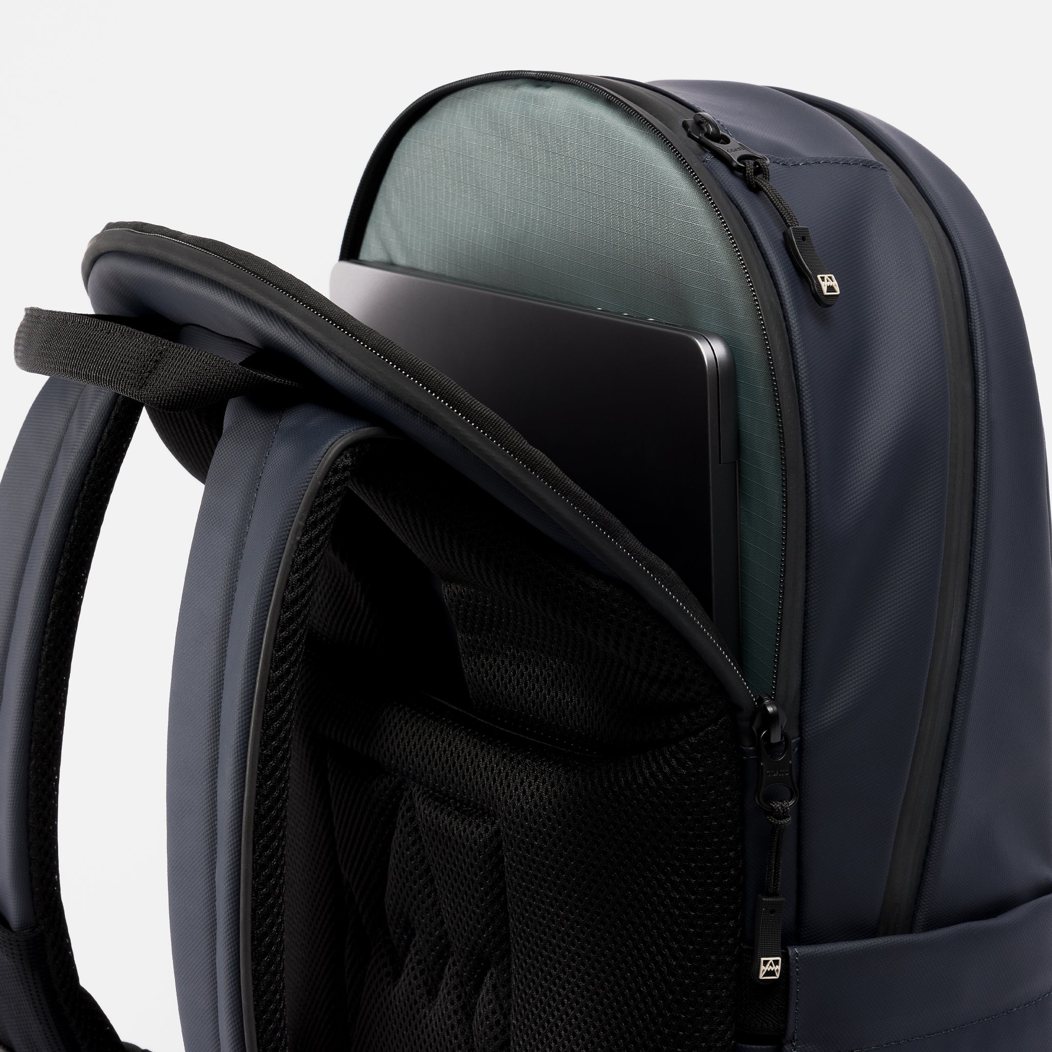 A studio shot of an Everyday Backpack 15L in Midnight Blue showing the laptop compartment which holds up to a 16" laptop