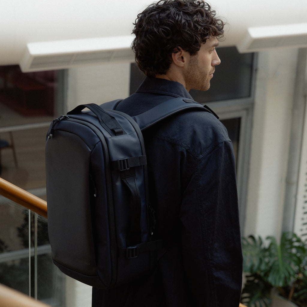 A man standing on stairs with a Midnight Blue Hybrid Backpack 20L on his back