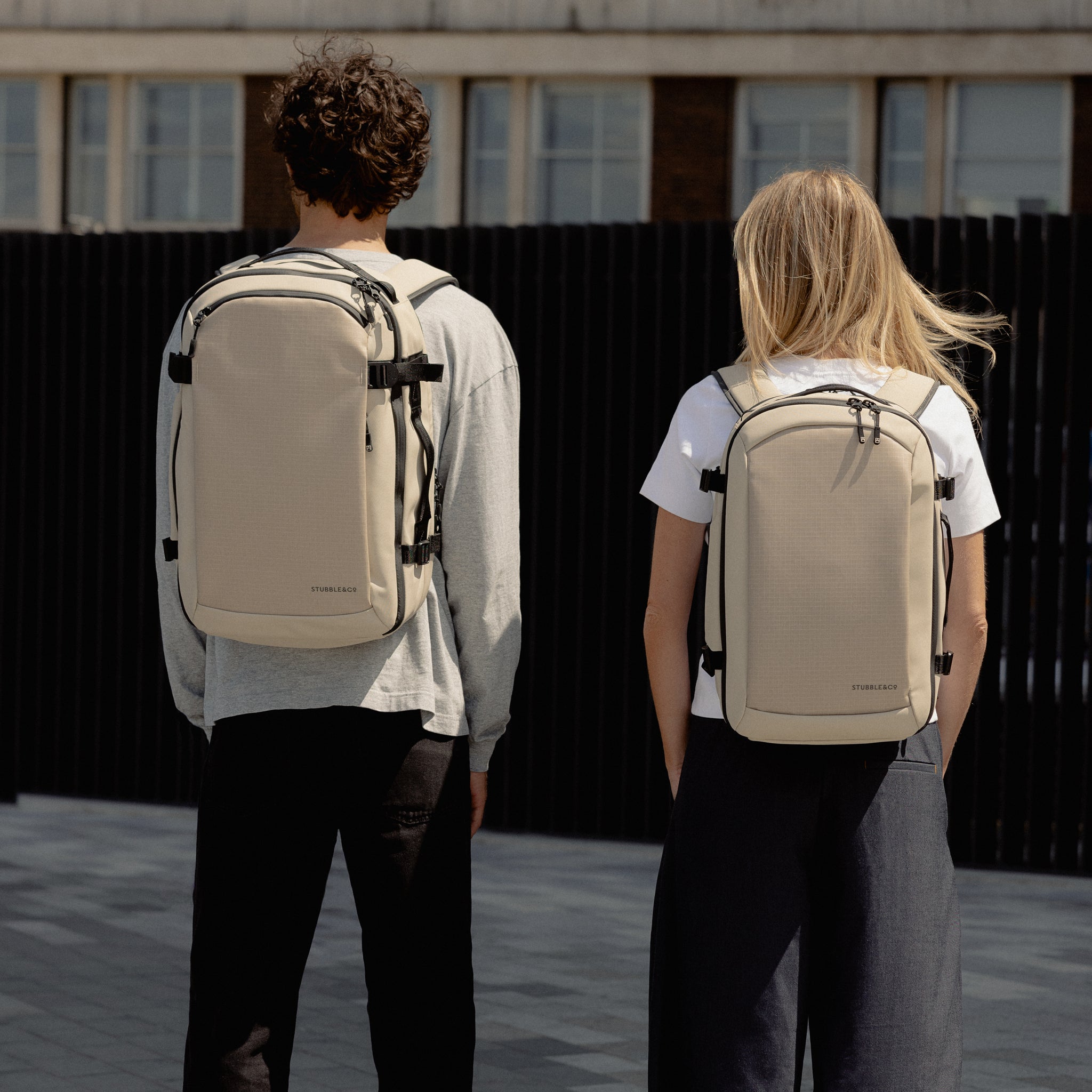 a mand and woman facing away wearing Sand Hybrid Backpack 20L on their backs