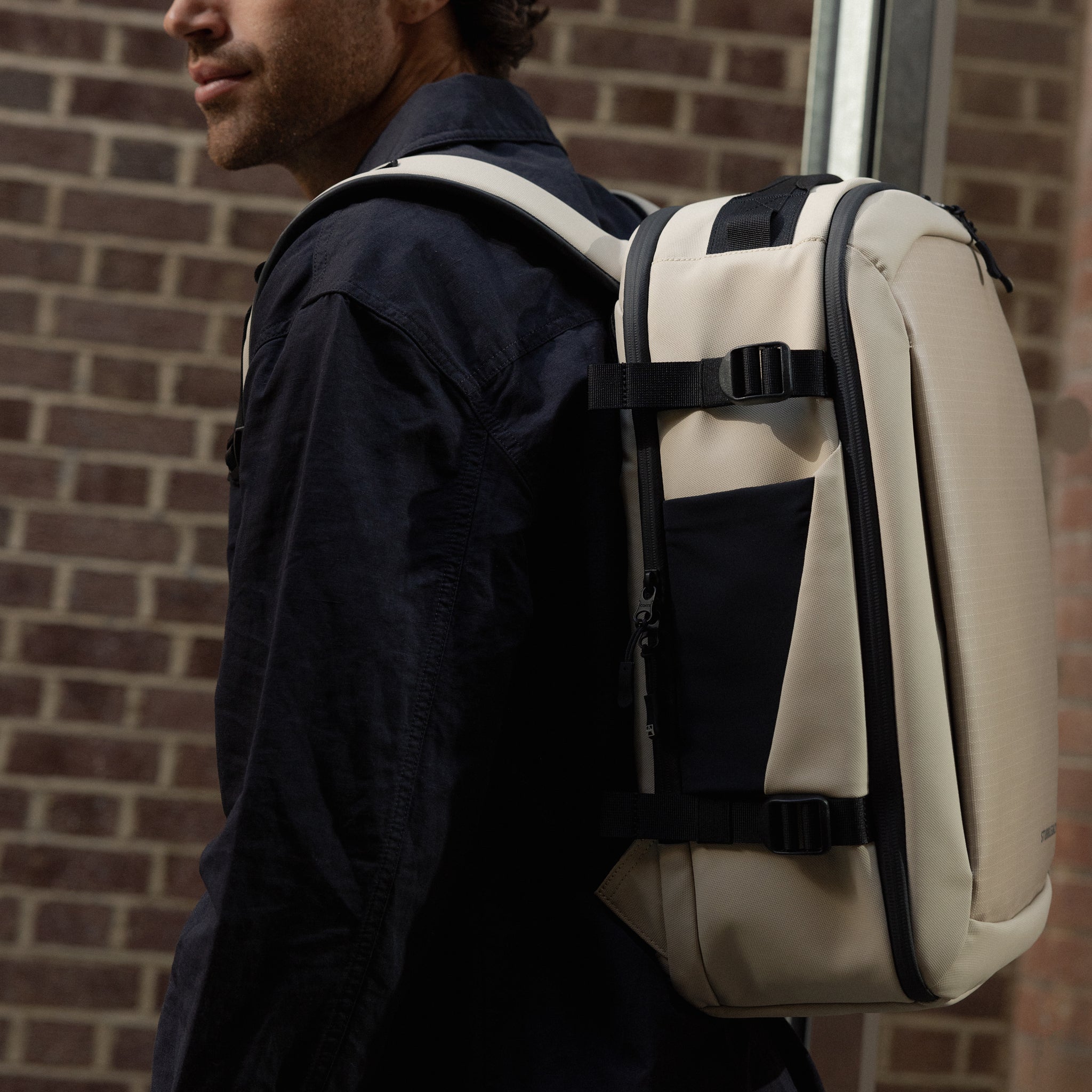 a man wearing a Sand Hybrid Backpack 20L on his back
