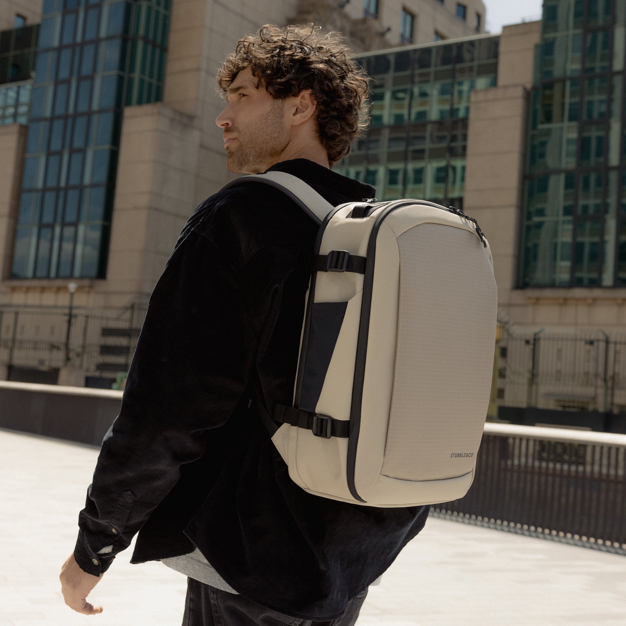 A man walking with a Hybrid Backpack 20L in Sand on his back