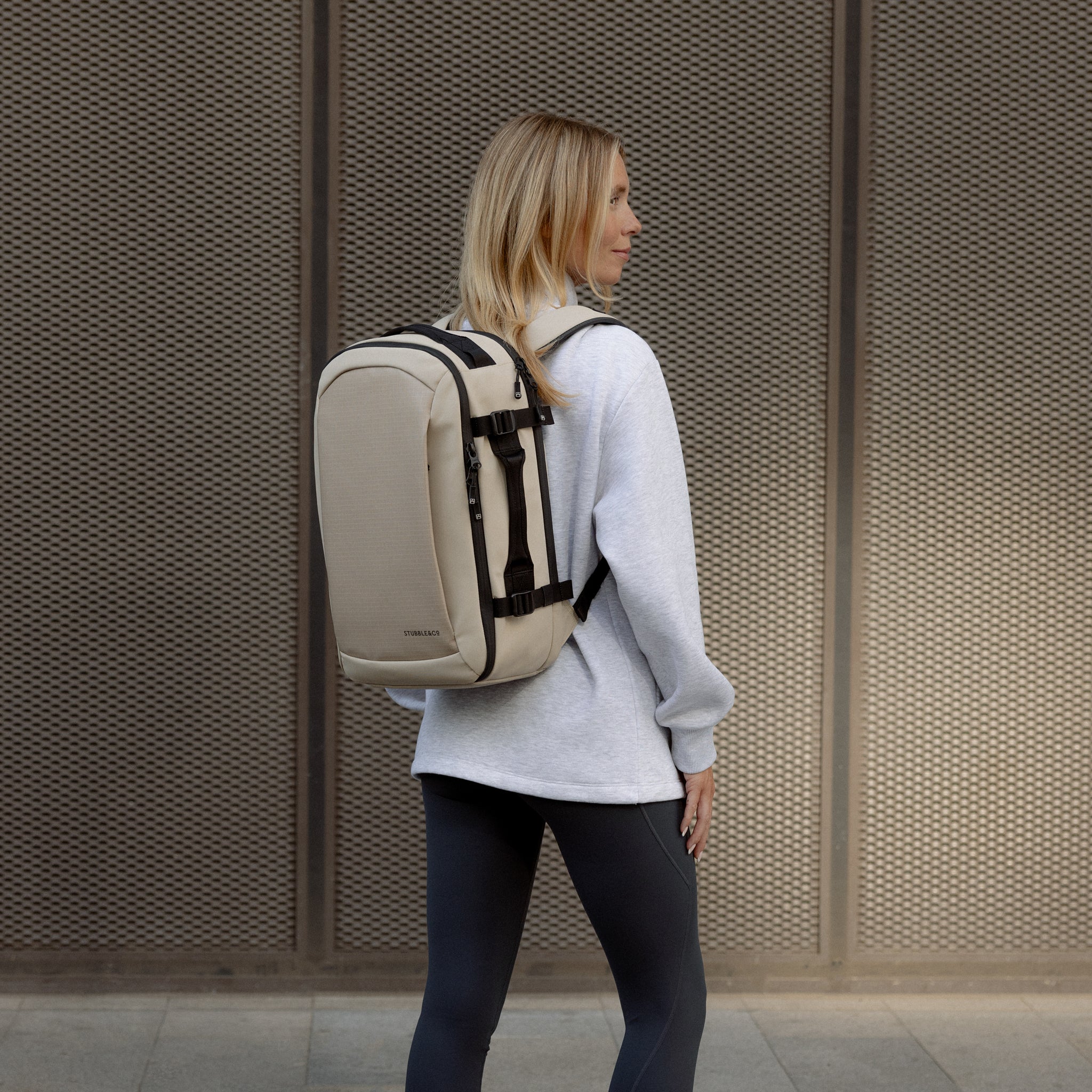 A woman wearing a Hybrid Backpack 20L in Sand on her back
