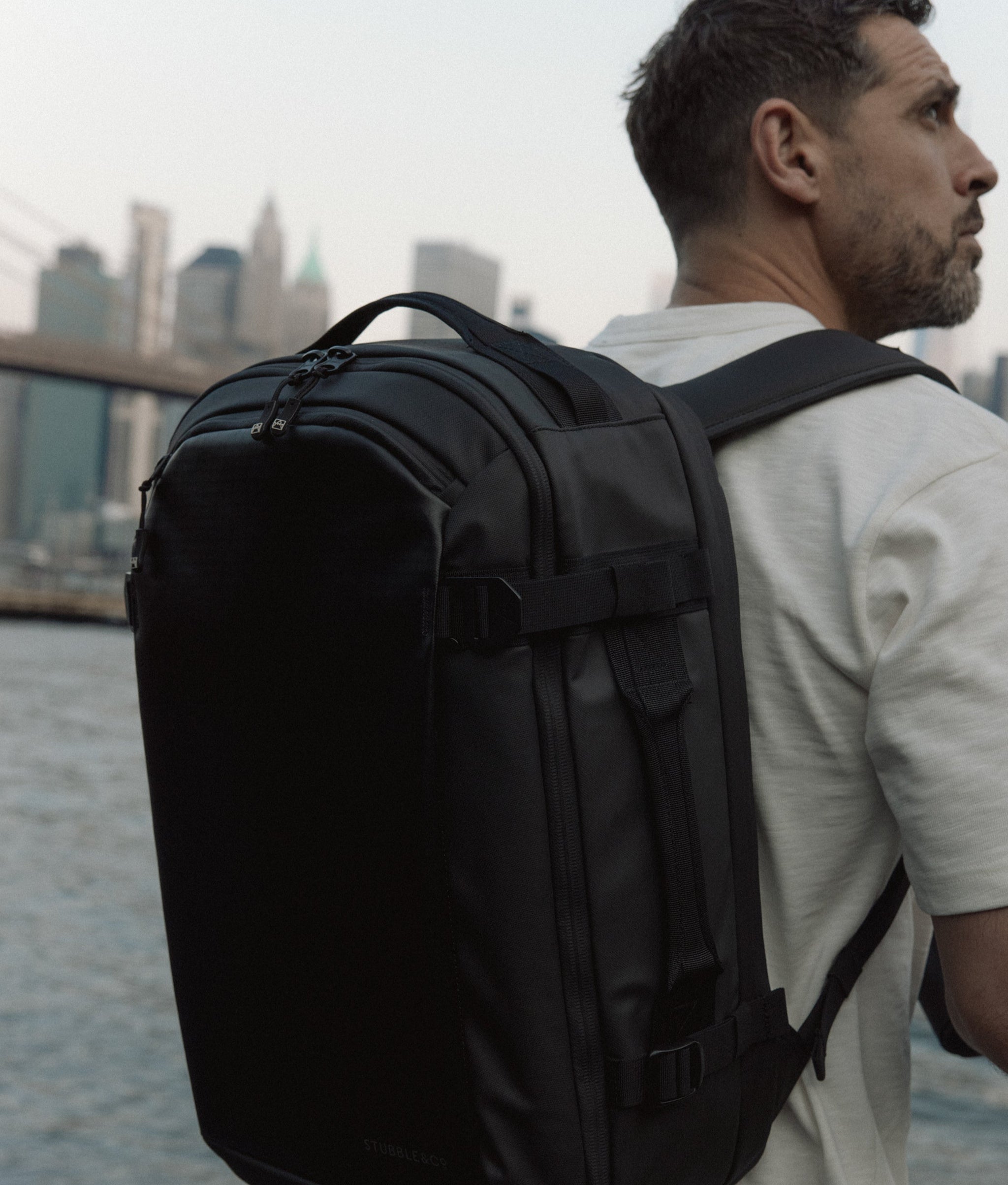 A man wearing a Hybrid Backpack 30L on his back with New York city in the backgorund