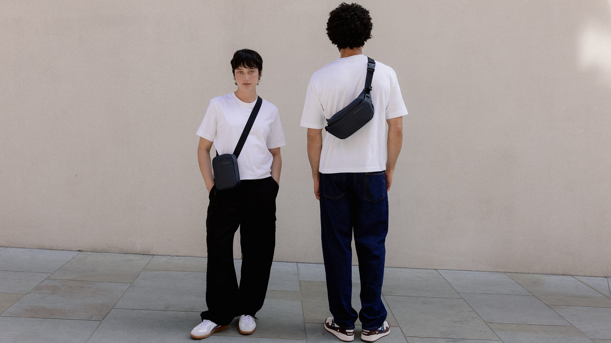 A man and woman wearing midnight blue small bags including the crossbody and shoulder bag