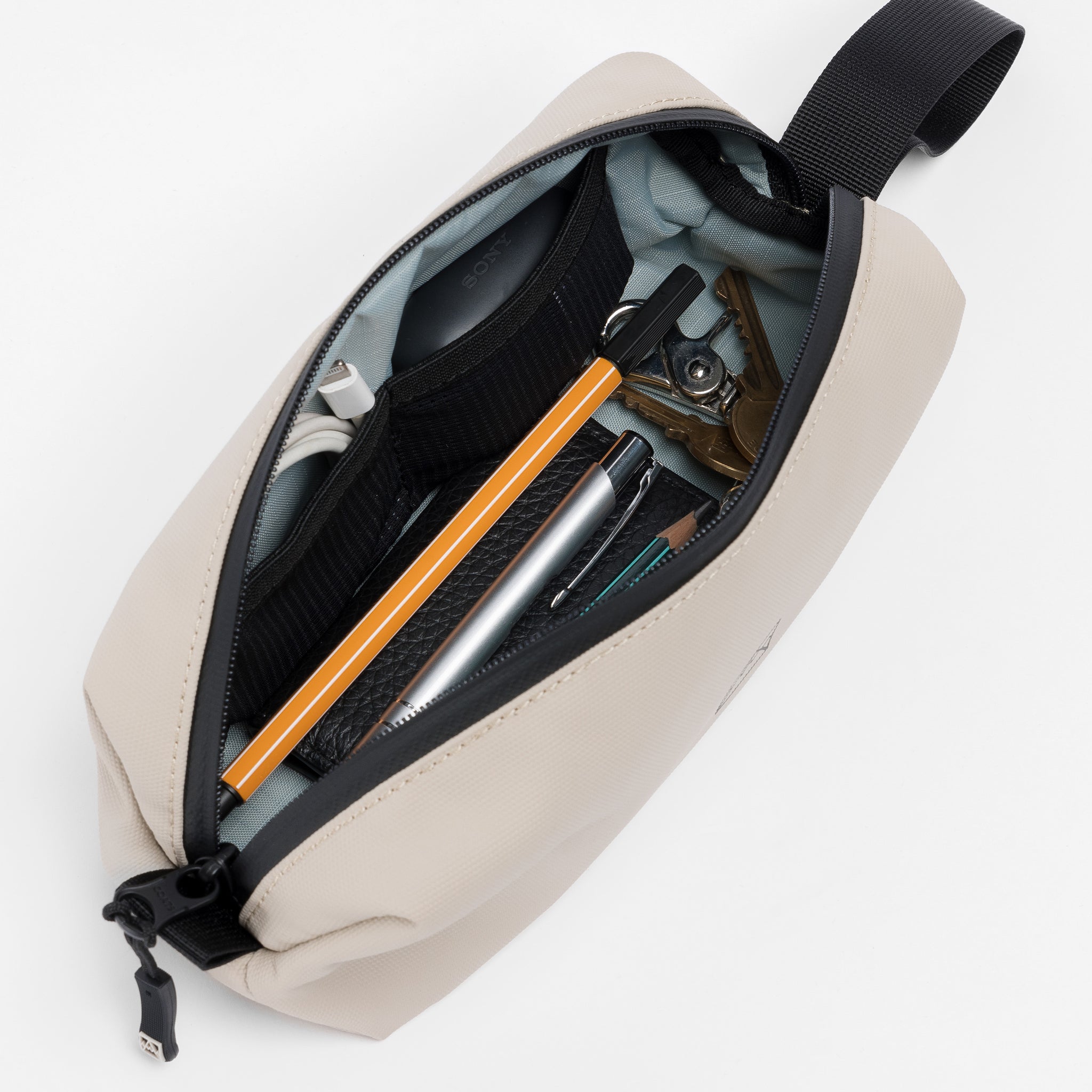 A studio shot of the interior of the Pencil Case in Sand packed with daily essentials