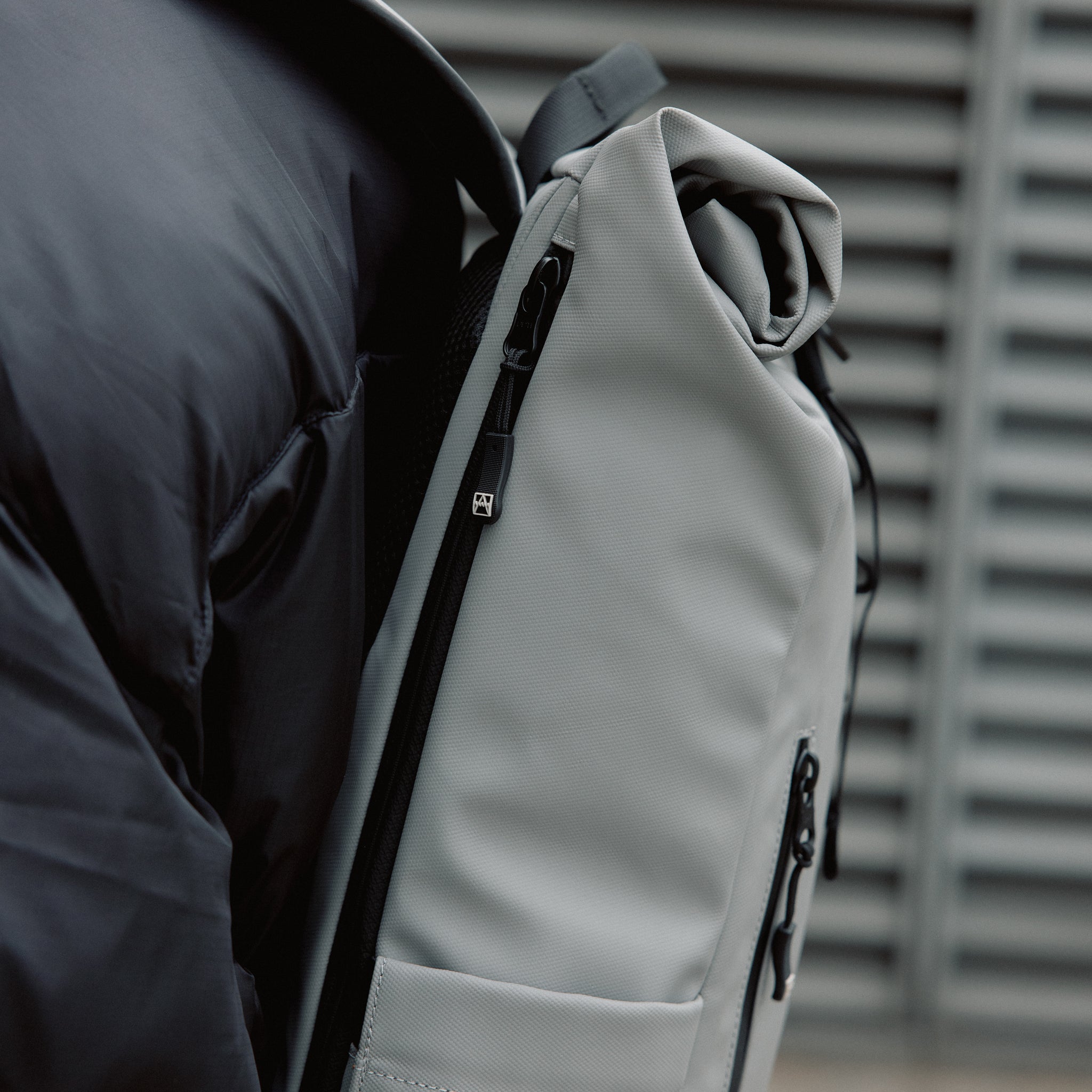 Close up of a person wearing the Roll Top 15L in Concrete