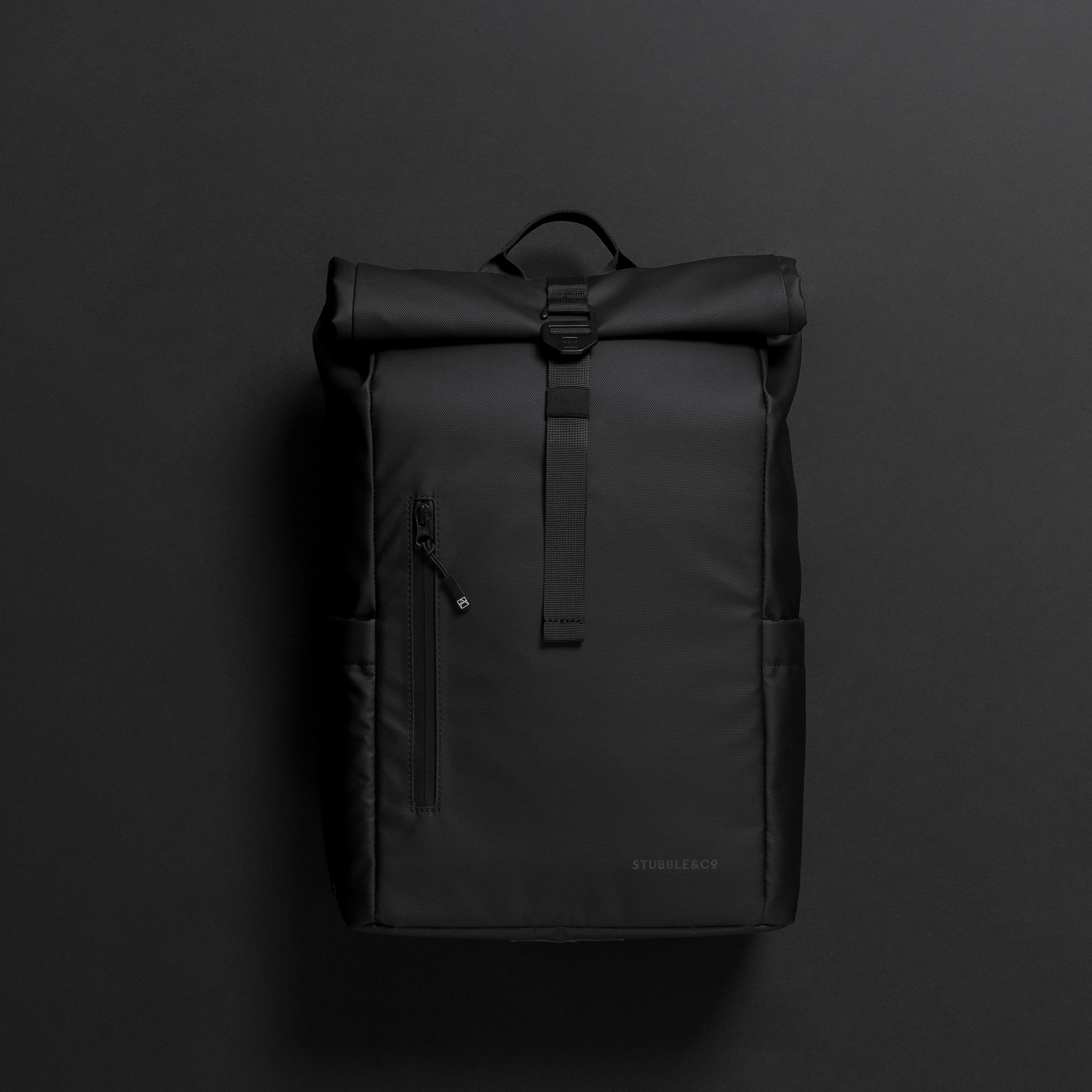 A front view of an All Black Roll Top 15L on a black background