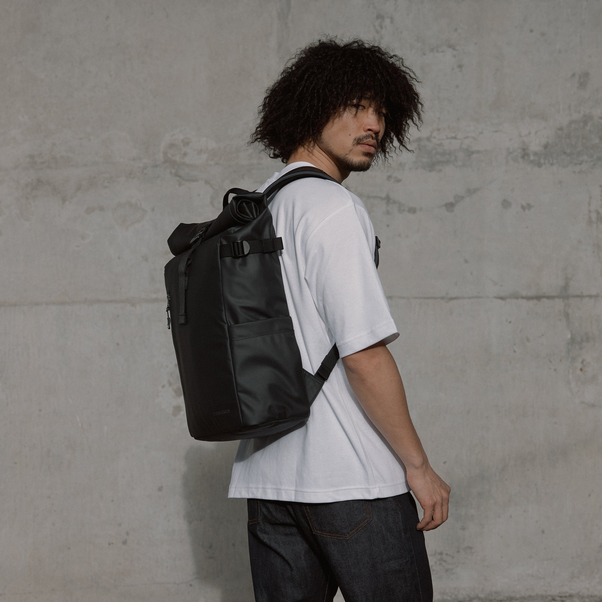 Man wearing The Roll Top 20L Backpack in All Black