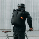 Man wearing The Roll Top 20L Backpack in All Black on a bike