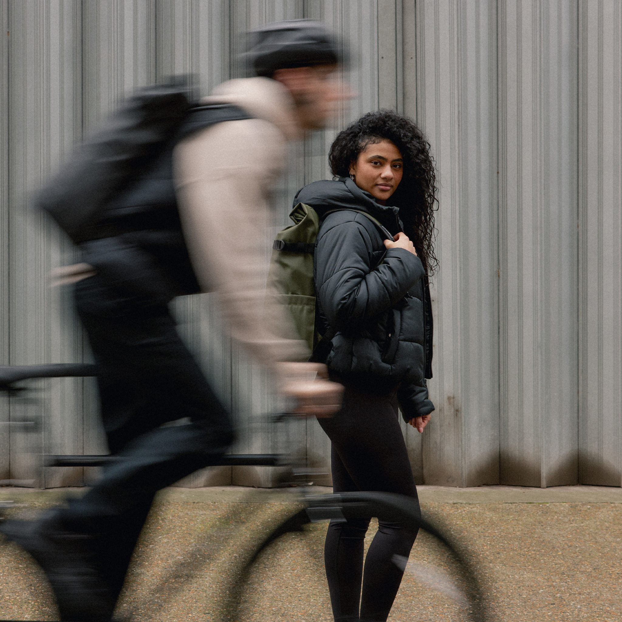 A man cycling and woman wearing a Roll Top 30L in Urban Green on her back
