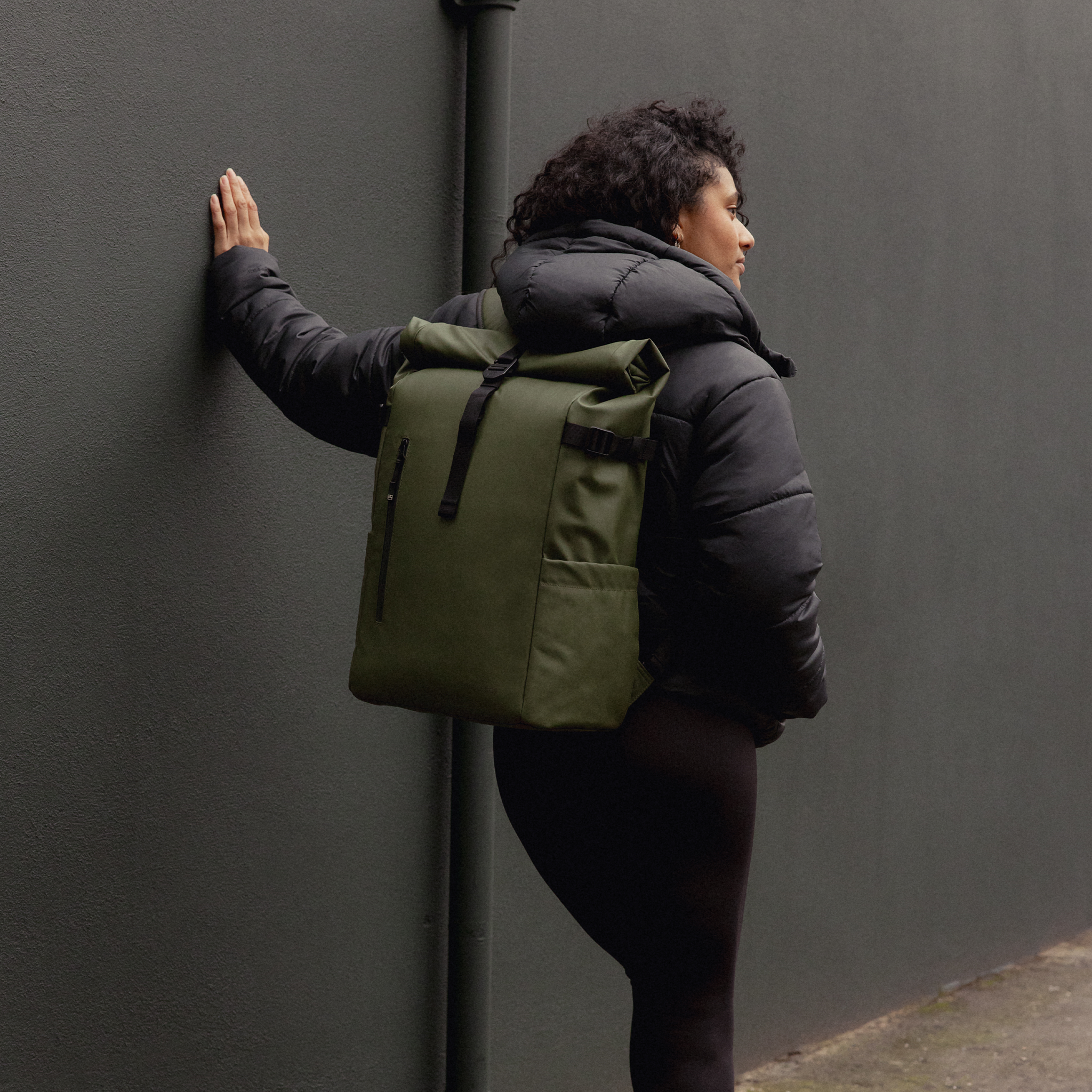 A woman facing away wearing a Roll Top 30L in Urban Green on her back