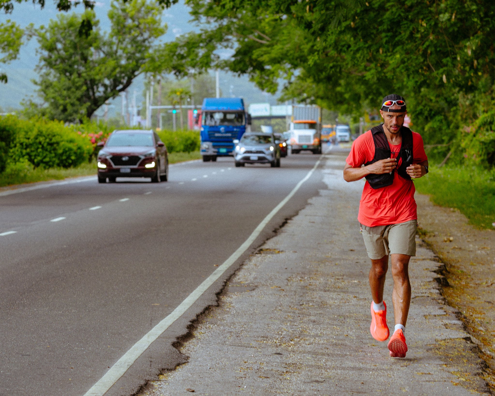 A man running along the pavement with roads driving past