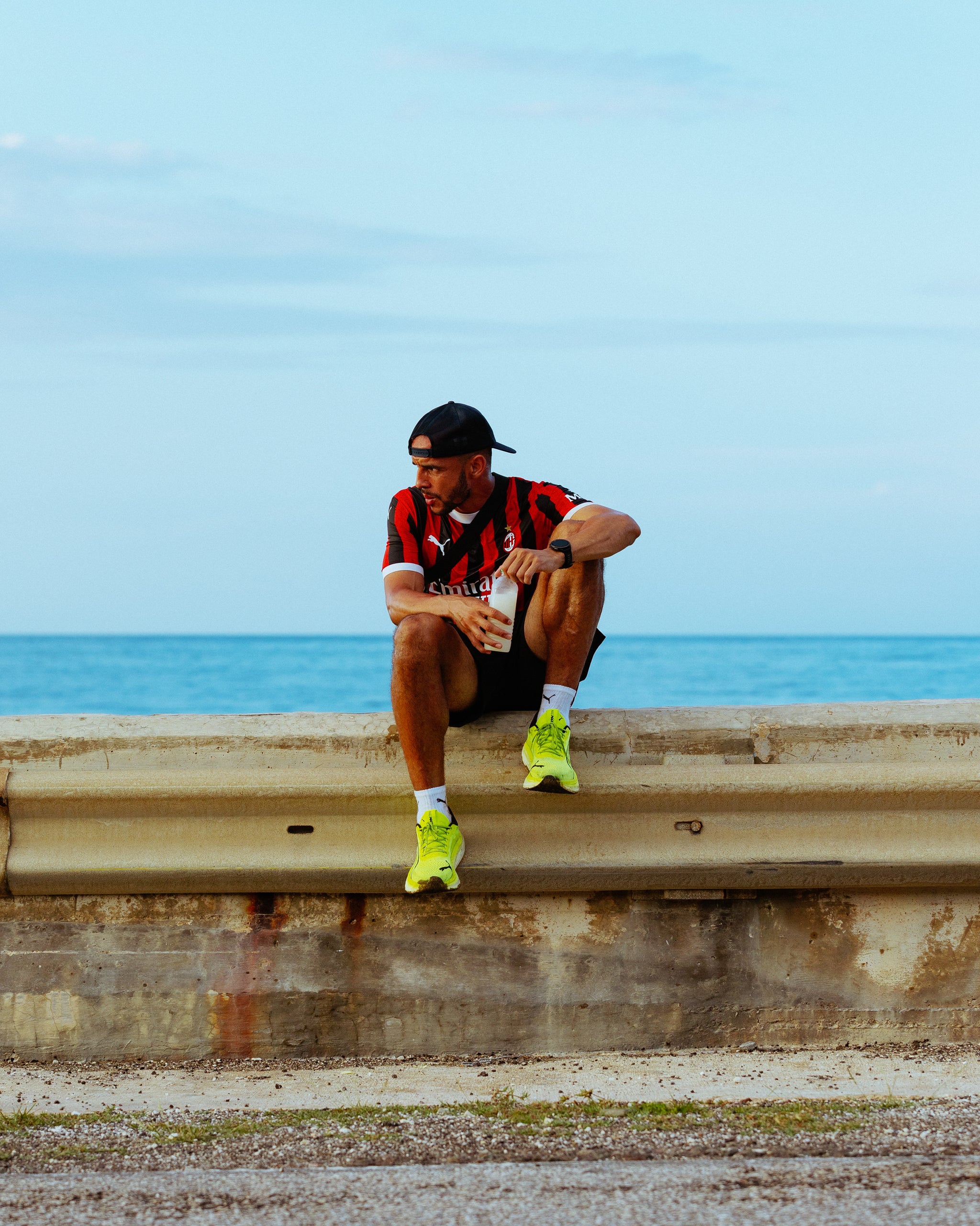 A man sitting on the sea wall drinking water