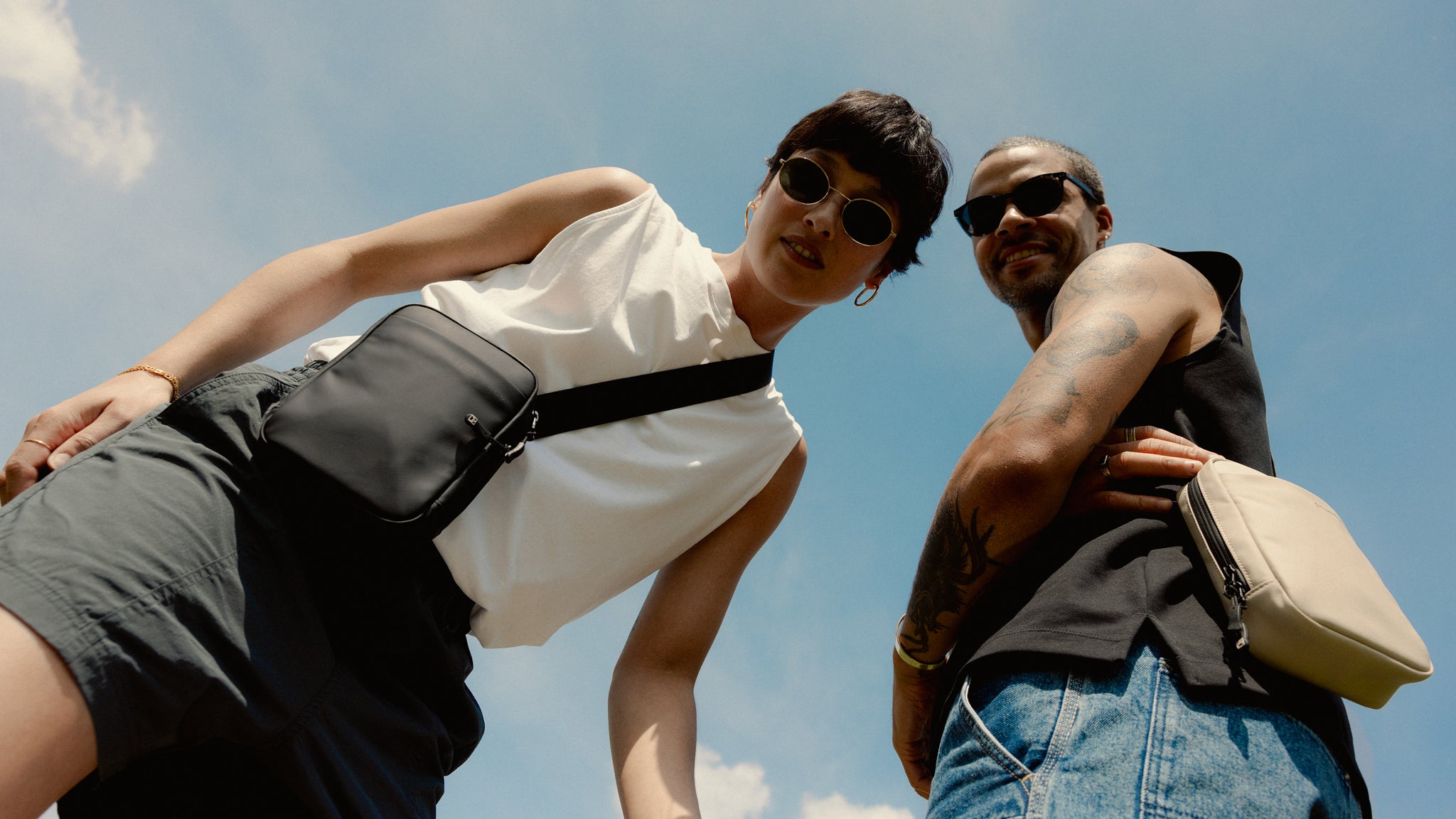 A man and woman looking down at camera wearing the new shoulder bag