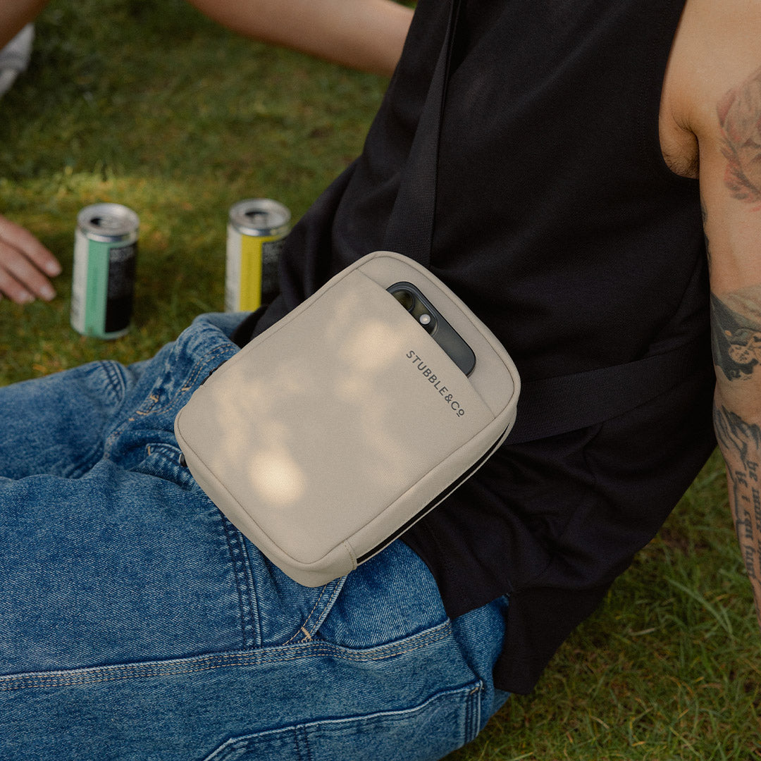 a close up of a Sand shoulder bag with a phone in the front slip pocket