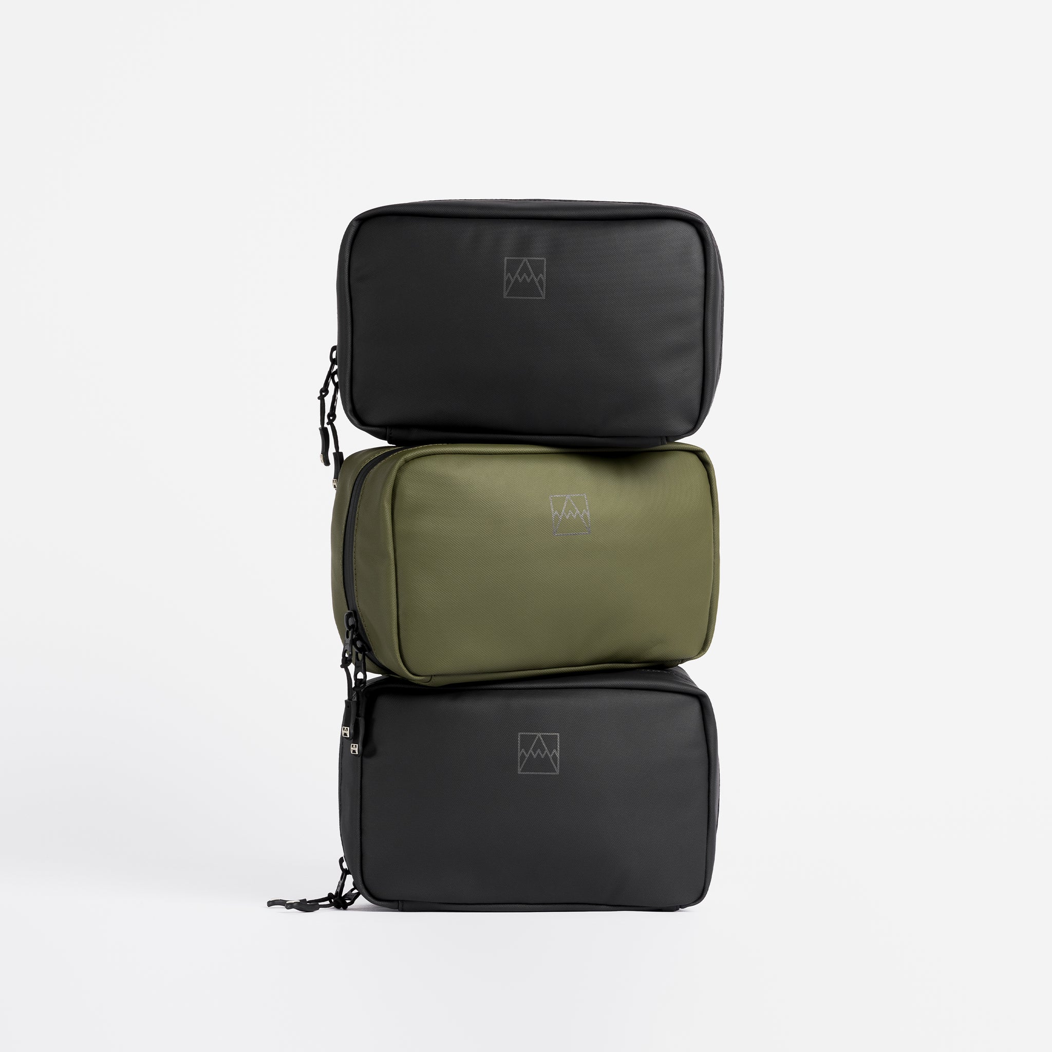 A studio shot of All Black and green tech bags stacked on top of eachother