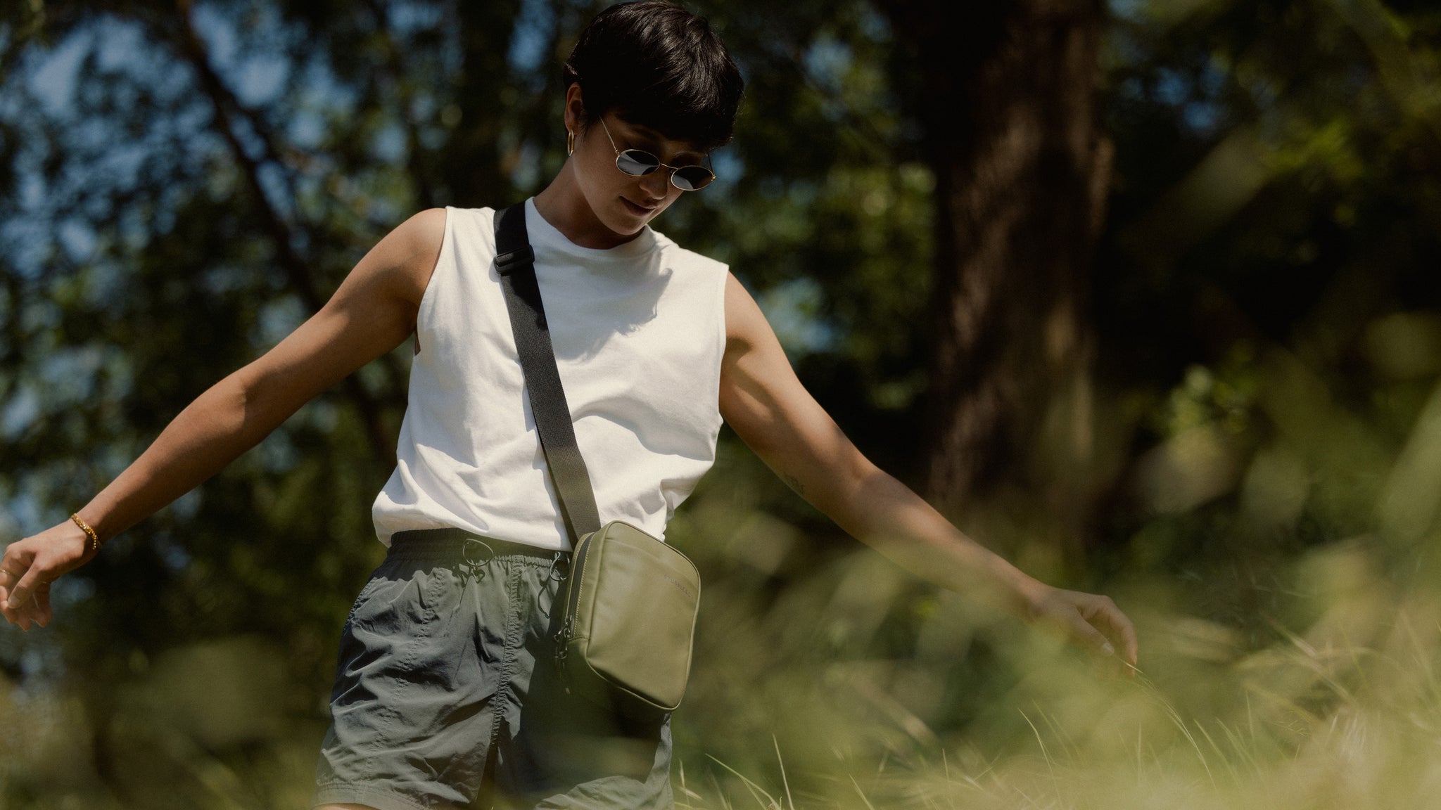 a woman standing in a field wearing an urban green shoulder bag