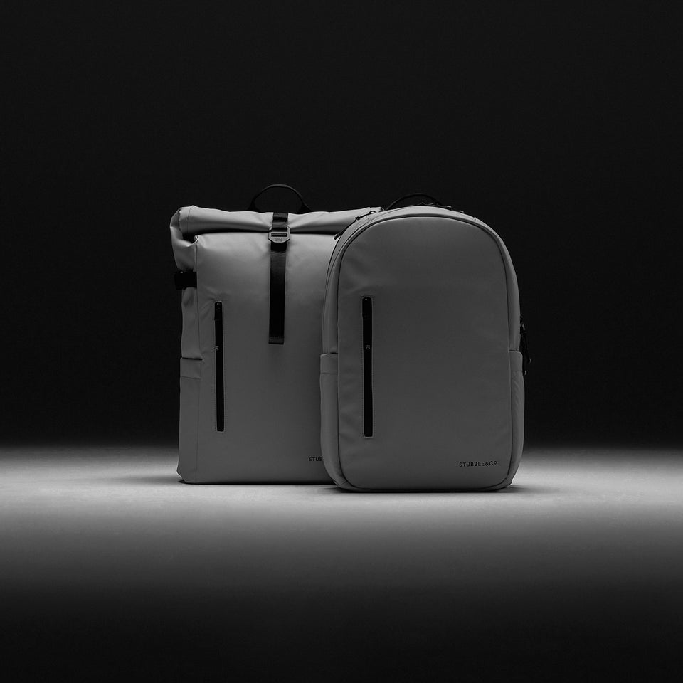 a studio shot of a concrete roll top and everyday backpack side by side