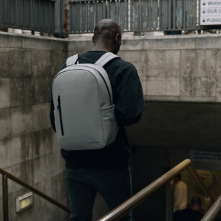 Man wearing grey backpack walking down steps into underground