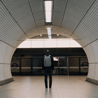 Man standing in the underground station wearing grey backpack