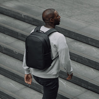 Man wearing black everyday backpack walking up steps