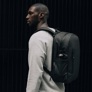 Side view of a man wearing The Everyday Backpack in All Black.