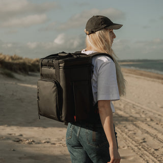 Women wearing cooler backpack in black at a beach