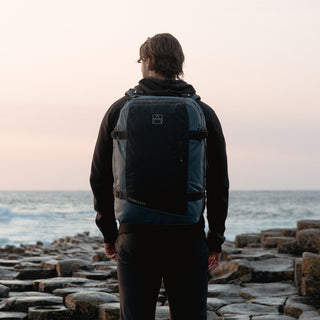 Man wearing the Tasmin Blue Adventure Bag, from the back while standing on the beach.