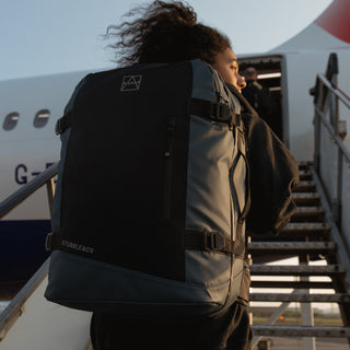 Close up of a woman wearing the Tasmin Blue Adventure Bag as she boards a plane.