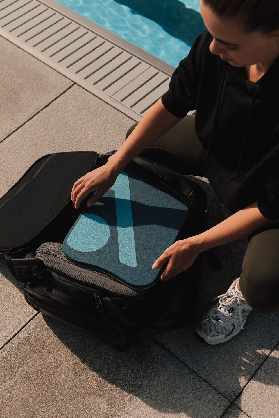 A woman putting a pool float into a black kit bag 40l 
