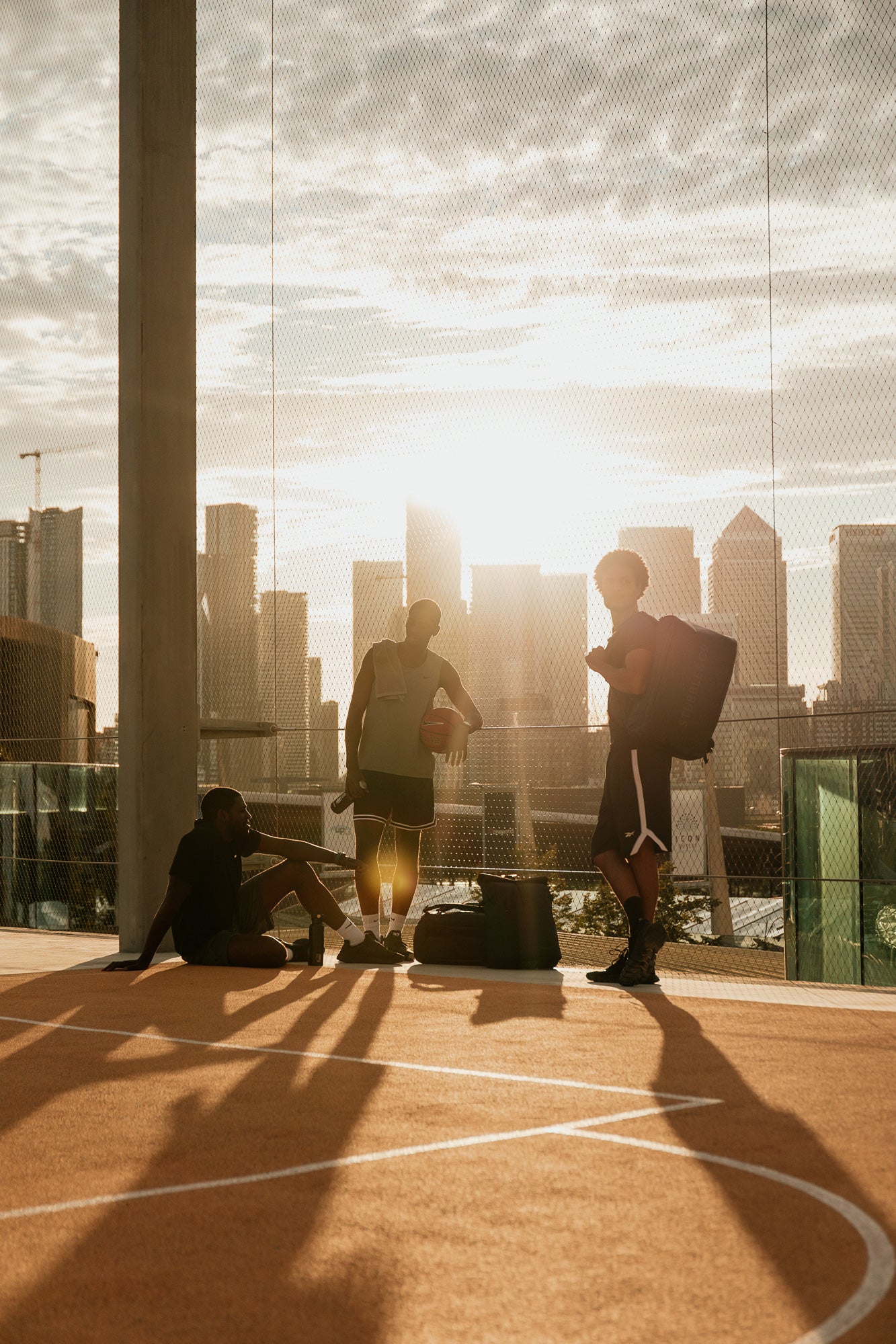 Three people on a rooftop court with a city skyline in the background