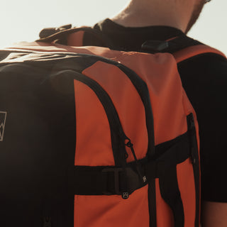 Close up of the top of the Ember Orange Adventure Bag being worn. Showing the top right hand corner and straps.