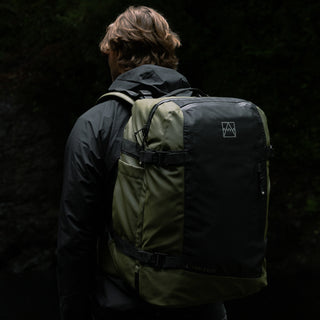 Back of a man wearing a black coat and the Urban Green Adventure Bag.