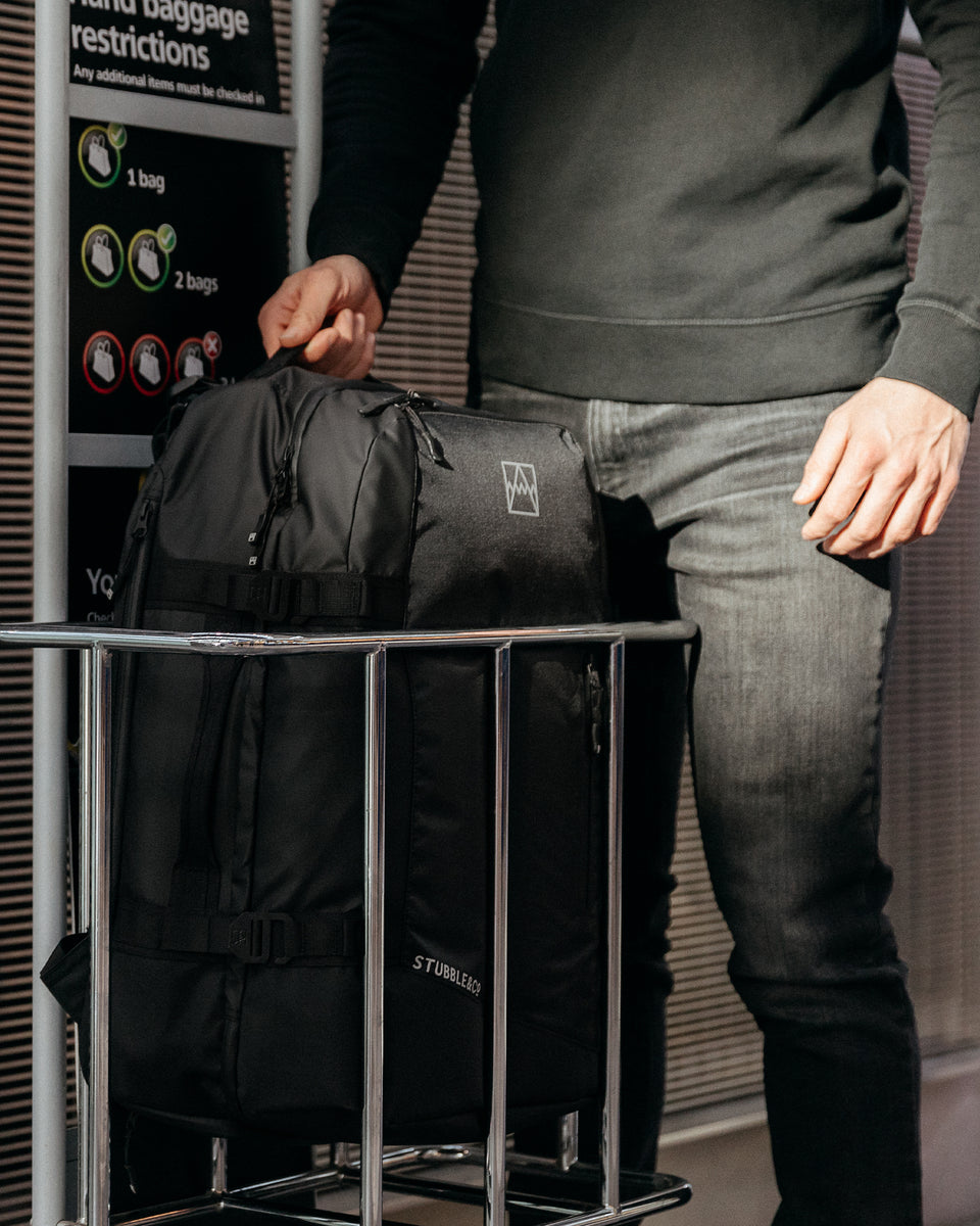 A man placing an Adventure Bag into the bag size checker at an airport