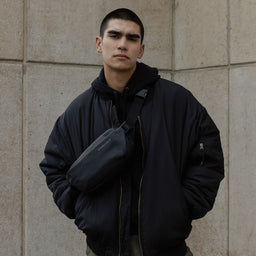 Male model standing with All Black crossbody on his front