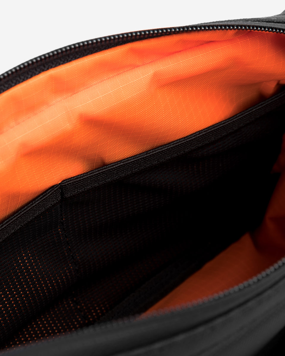 Interior view of an All Black Crossbody with internal pockets and orange lining