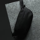 Close up of an All Black Crossbody bag on a concrete surface