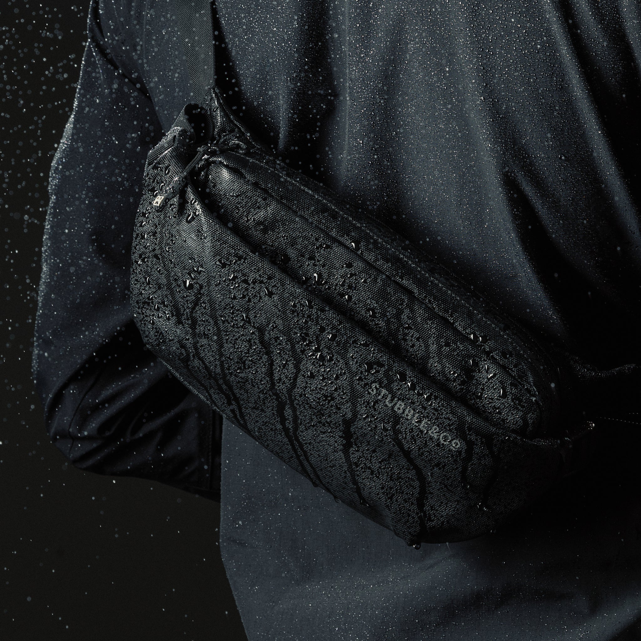 Close up of a person wearing an All Black Crossbody bag in the rain