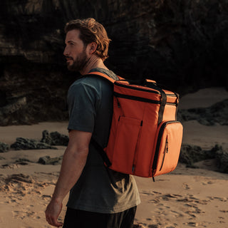 Side view of a man wearing the Emerb Orange Cooler on the beach.
