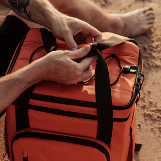 Ember Orange Cooler being opened on the beach.