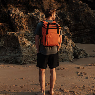 Back view of a man wearing The Cooler in Ember Orange on the beach.
