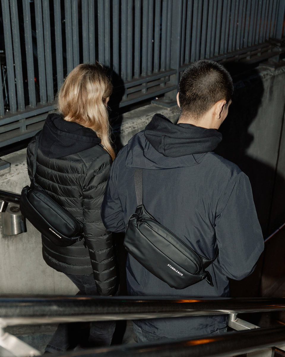 Man and women walking down stairs wearing black crossbody bags