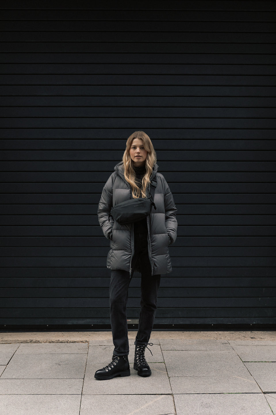 A women standing in view wearing an All Black crossbody bag on her front