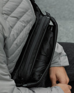 A close up view of an All Black Crossbody bag showing an umbrella in the front expandable pocket