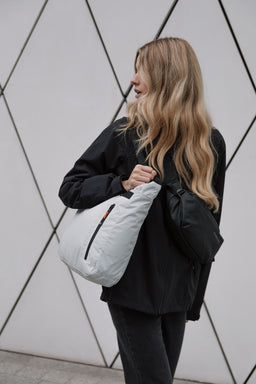 A woman carrying an Off White tote bag and wearing a black crossbody bag