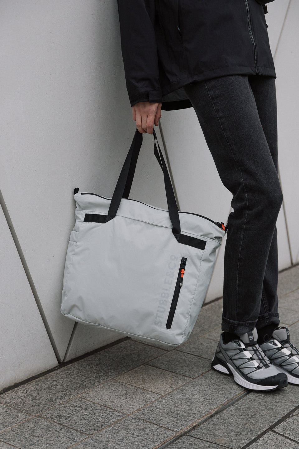 a close up of a woman holding an Off-White tote bag at her side
