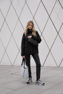 A woman holding an Off White Ultra Light packable bag and wearing a black crossbody bag